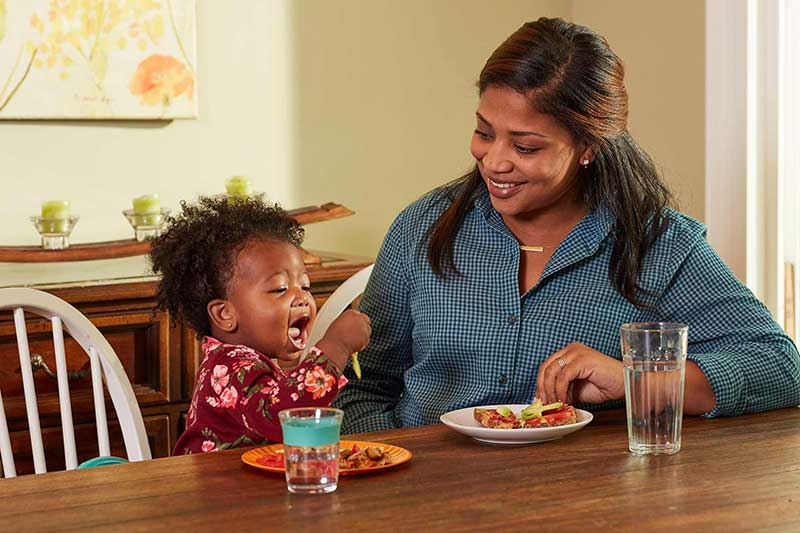 happy toddler eating with mom
